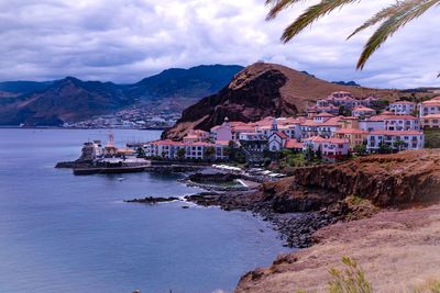 Scenic view of beach by city against sky