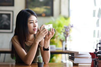 Young woman photographing while sitting on table at restaurant