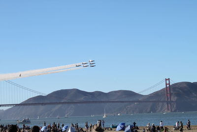 Group of people on mountain against clear blue sky