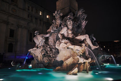 Statue of fountain in city at night