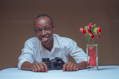 Portrait of a smiling young man sitting on table