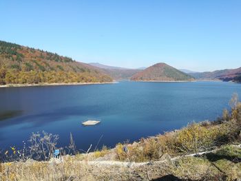 Scenic view of lake and mountains against clear blue sky