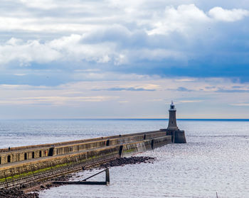 Lighthouse by sea against sky