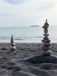 Stack of pebbles at beach against sky
