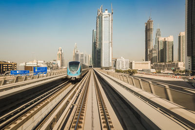 Railroad tracks amidst buildings in city against sky