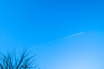 Low angle view of vapor trail against clear blue sky