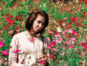 Portrait of young woman standing by plants