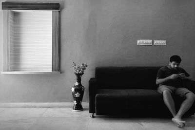 Full length of man sitting on sofa at home