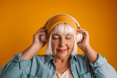 Portrait of young woman against yellow background