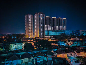 Illuminated buildings in city against sky at night