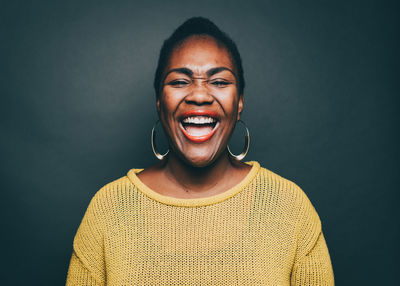 Mid adult woman laughing over gray background