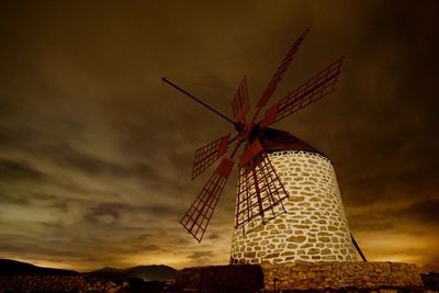 Low angle view of traditional windmill against sky during sunset