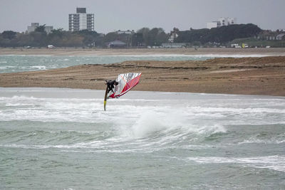 Person paragliding in sea against sky