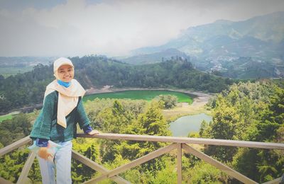 Portrait of beautiful women standing on railing against mountains and lake