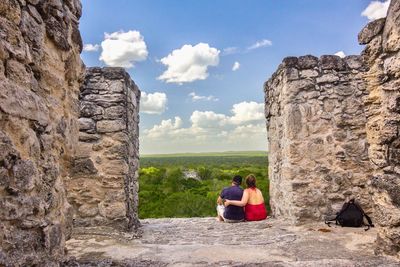 Rear view of couple sitting at old ruin