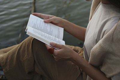 Woman sitting with book sitting by river