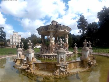 Statue in pond against sky