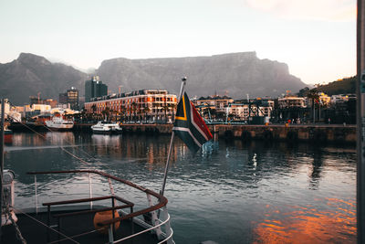Boats moored at harbor by buildings in city against sky