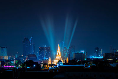 Illuminated buildings in city against sky at night