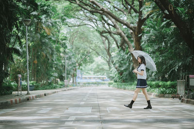 Full length of woman standing on footpath amidst trees