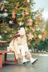 Woman sitting on seat against trees