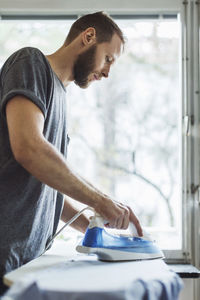 Side view of man ironing shirt at home