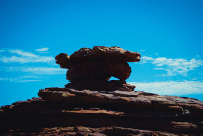 Low angle view of stack rock against blue sky