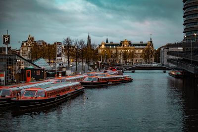 Boats moored in river against buildings in city