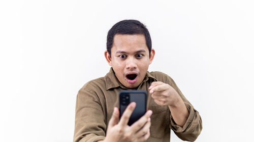 Portrait of mid adult man using smart phone against white background