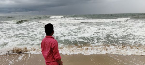 Rear view of man looking at sea against sky