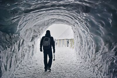 Rear view of man walking in ice cave