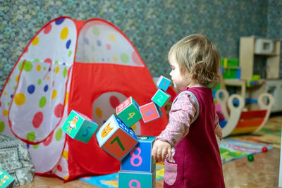 Cute girl playing with toy blocks at home