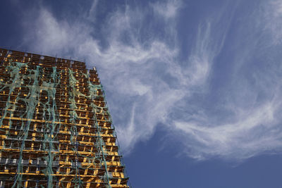 Low angle view of building covered with scaffoldings against sky