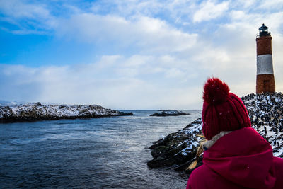 Rear view of woman looking at sea against sky during winter