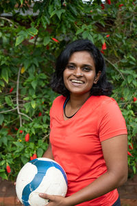 Portrait of smiling young woman holding ball