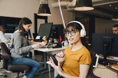 Portrait of female it professional using digital tablet while coworkers working in creative office