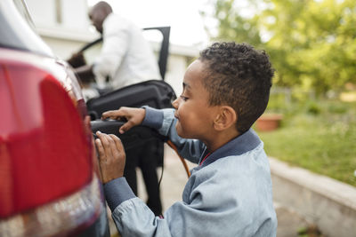 Side view of boy looking while charging electric car