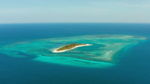 Tropical island canimeran with sandy beach in the blue sea with coral reef, top view. 