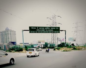 Information sign on road against sky in city