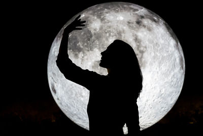 Silhouette woman standing against sky at night