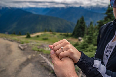 Close-up of hands on mountain against sky