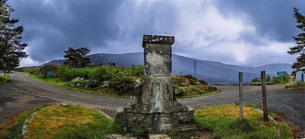 Road passing through landscape against cloudy sky