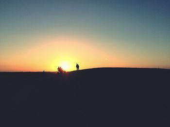 Silhouettes of men riding on quadbike in desert