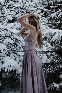 Portrait of young woman standing against tree