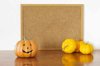 Jack o lantern and pumpkins against bulletin board on table