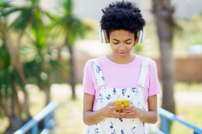 Portrait of young woman standing against fence