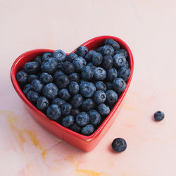 Blueberries in bowl on pink background, copy space