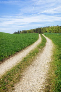 Road amidst field against sky