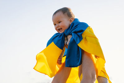 Little boy wrapped in yellow and blue flag of ukraine in outdoors. independence day.