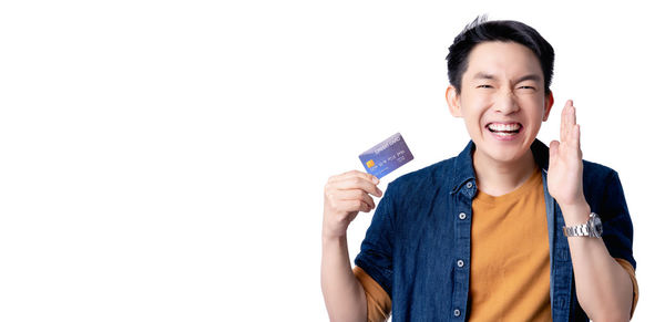 Smiling young man holding camera against white background